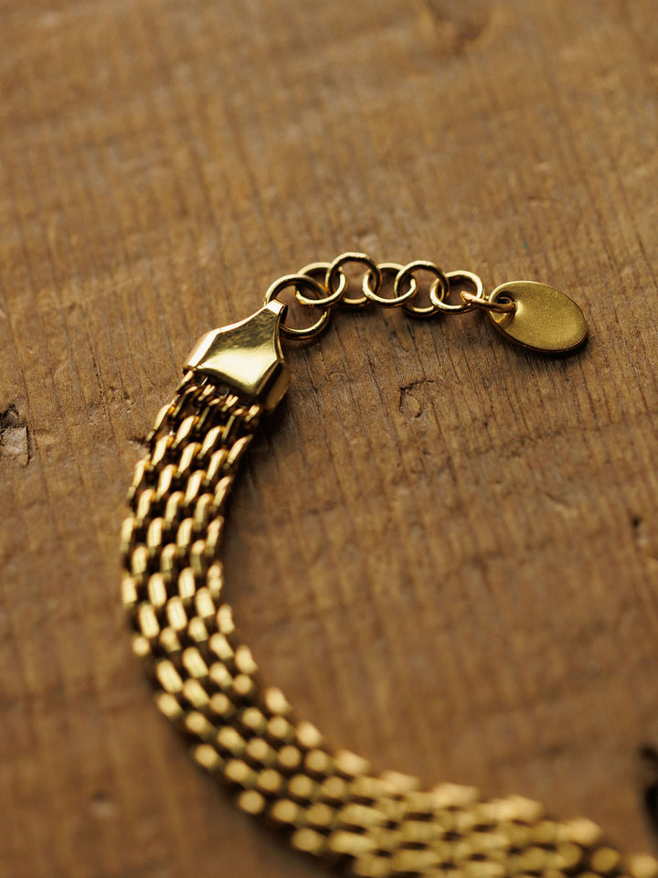 The Vienna Bracelet by Savannah Sevens western life{&}style is a hypoallergenic 18K gold filled chain with a clasp and extension links, shown in a close-up on a textured wooden surface.