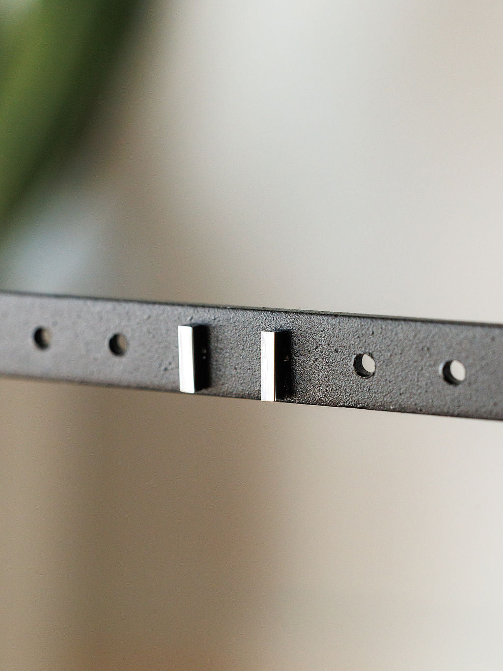 Close-up of a black leather belt with silver keepers and evenly spaced holes, set against a blurred background—ideal to pair with minimalist accessories like the Lexington Earrings by Savannah Sevens western life{&}style.