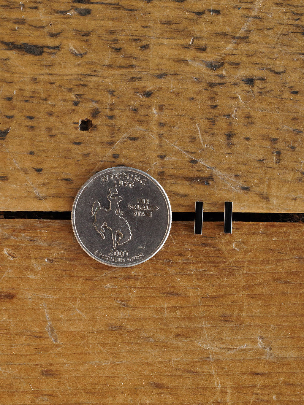 A 2007 Wyoming state quarter rests on wood beside two Lexington Earrings by Savannah Sevens western life{&}style, illustrating the earrings' size.