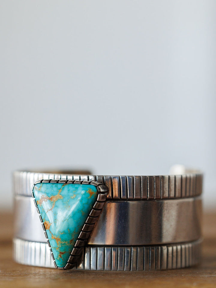 The Vallejo Cuff by Savannah Sevens western life{&}style is a vintage sterling silver bracelet featuring a large triangular turquoise stone with brown veining, set in a decorative bezel and accented by vertical engraved band lines.