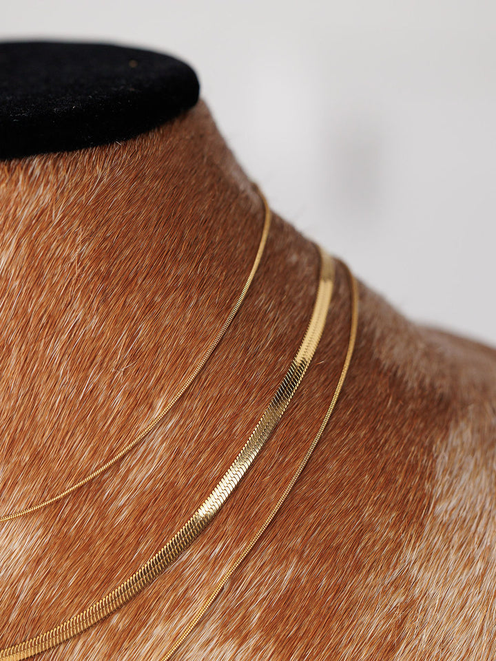 A close-up of a brown, short-haired dog's neck wearing the Lynden Necklace by Savannah Sevens western life{&}style, featuring a gold triple-layer design against a plain background.