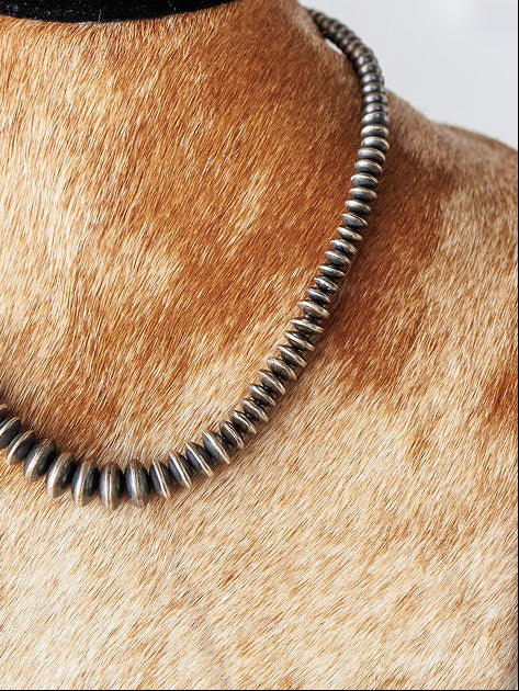 A close-up of the Saledo Necklace by Savannah Sevens western life{&}style, featuring graduated sterling silver Navajo pearl rondelle beads, shown on cowhide bust.