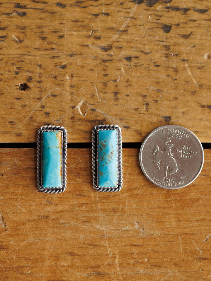 The Toano Earrings by Savannah Sevens western life{&}style feature rectangular turquoise bars with silver rope borders, shown beside a 2007 Wyoming state quarter for size. These Navajo handcrafted sterling silver earrings are striking and unique.