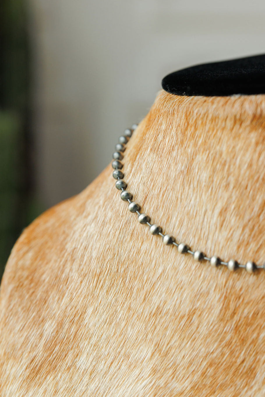 A close-up of the Sedalia Necklace by Savannah Sevens western life{&}style, a sterling silver Navajo pearl piece, displayed on a tan cowhide mannequin bust with a black velvet collar.