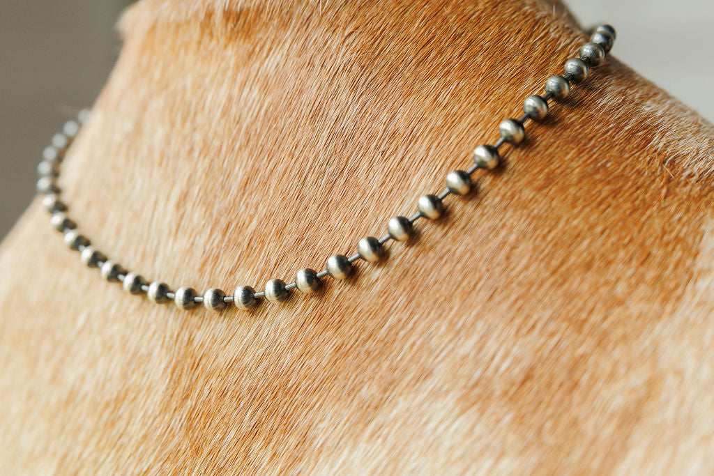 A close-up of the Sedalia Necklace from Savannah Sevens western life{&}style resting on the short, light brown cowhide