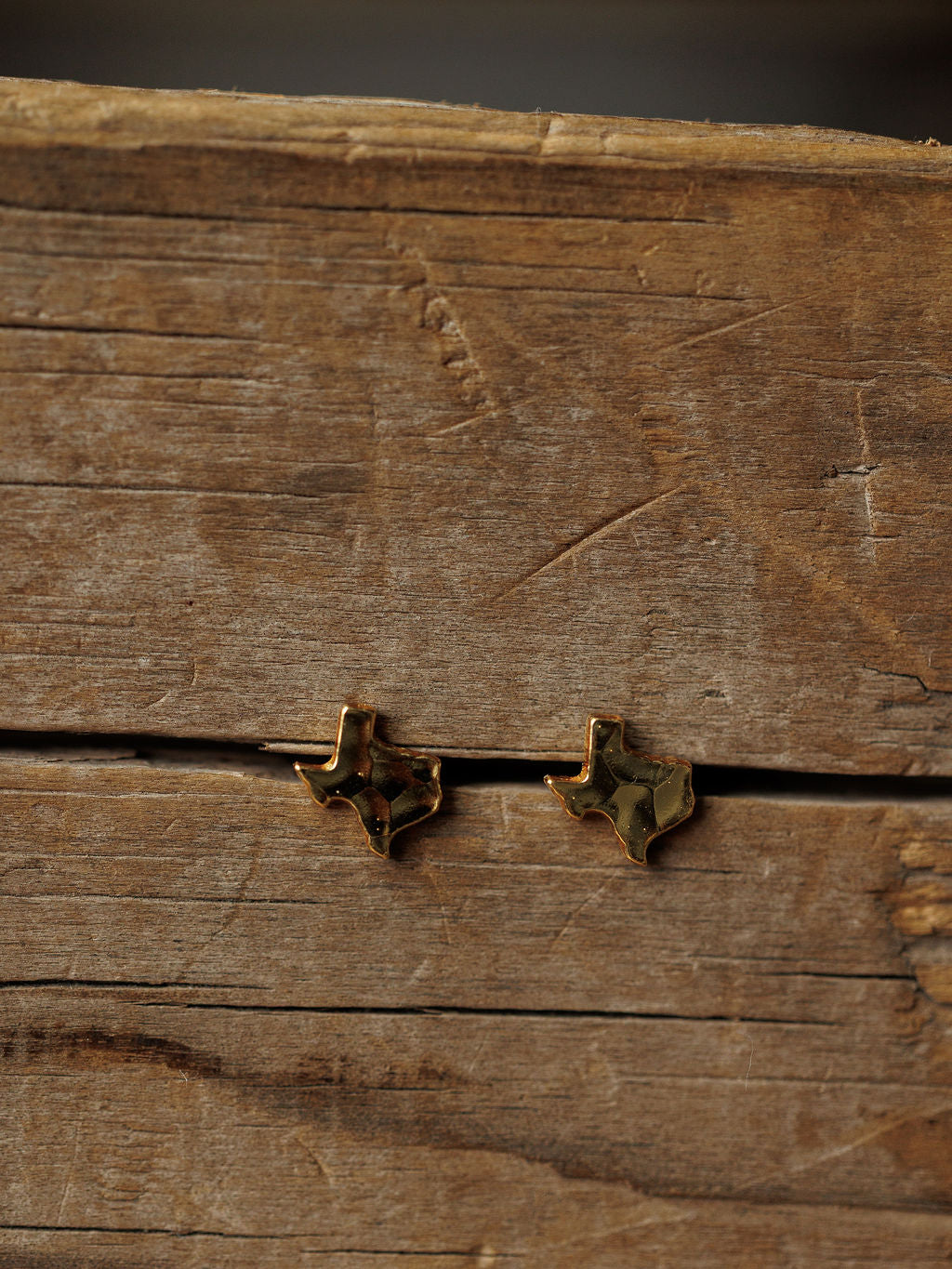 The Texas Earrings by Savannah Sevens western life{&}style are small, hammered gold studs shaped like Texas. Hypoallergenic and stylish, they add a unique western touch to any outfit.