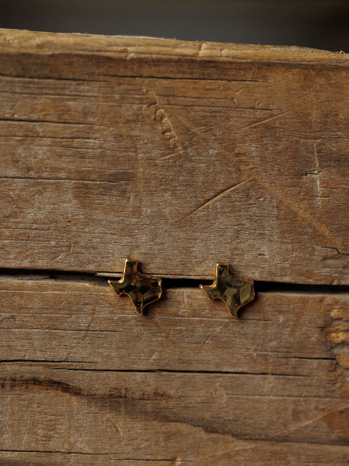 The Texas Earrings by Savannah Sevens western life{&}style are small, hammered gold studs shaped like Texas. Hypoallergenic and stylish, they add a unique western touch to any outfit.