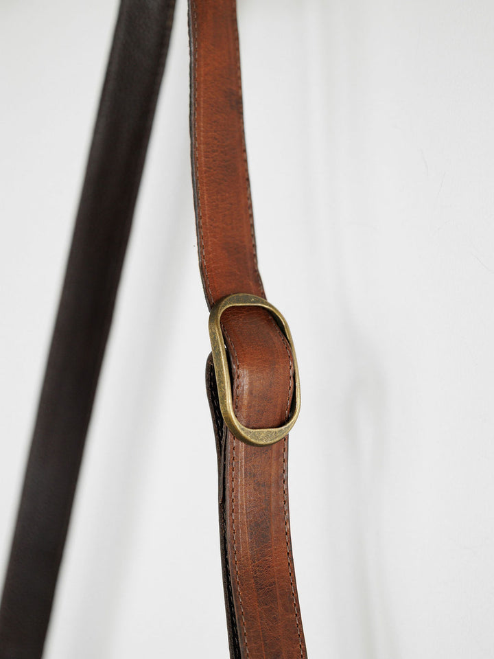 Close-up of The Chicota brown leather strap by Savannah Sevens western life{&}style, with visible stitching and antique brass buckle—ideal accent for a saddle tan crossbody bag for women against a white background.
