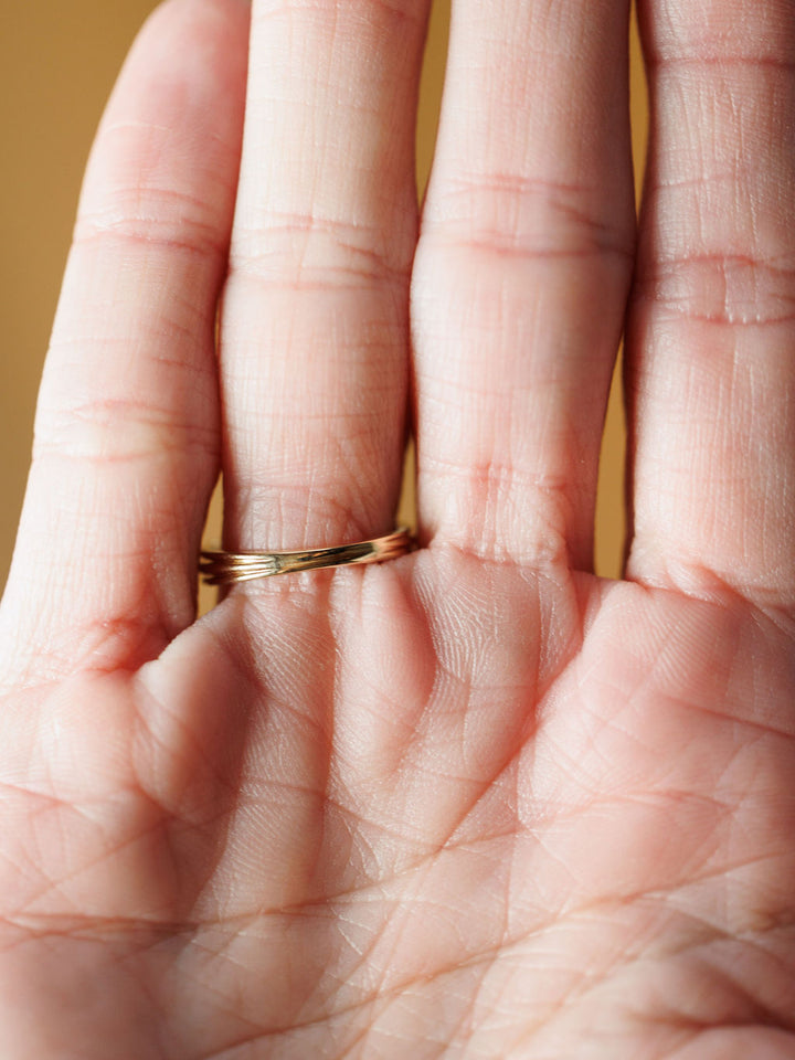 A close-up of an open hand with visible palm lines showcases the Diamond Milgrain Ring by Savannah Sevens western life{&}style on the ring finger against a warmly glowing, softly blurred background.