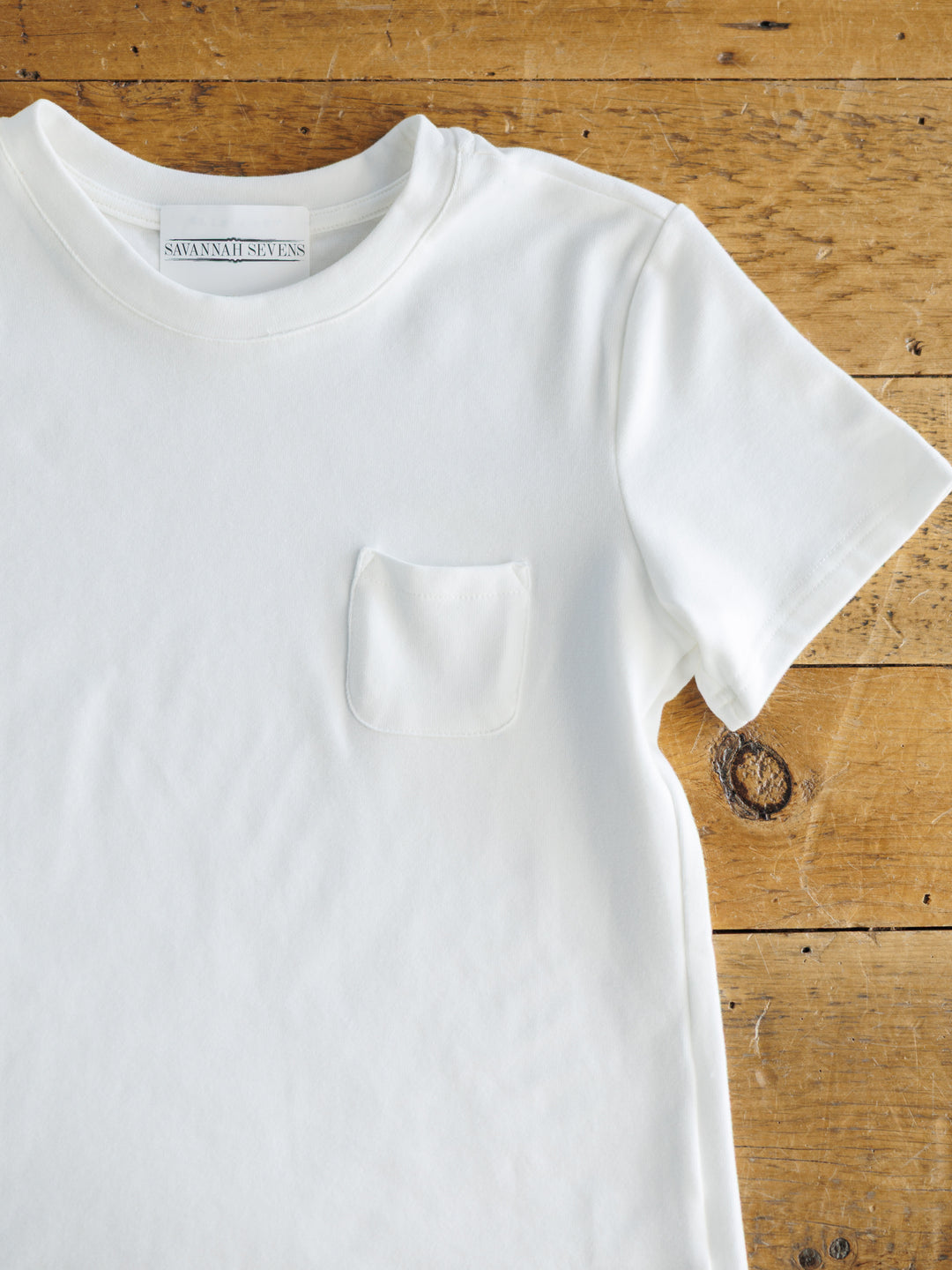 White t-shirt with a pocket on a wooden surface