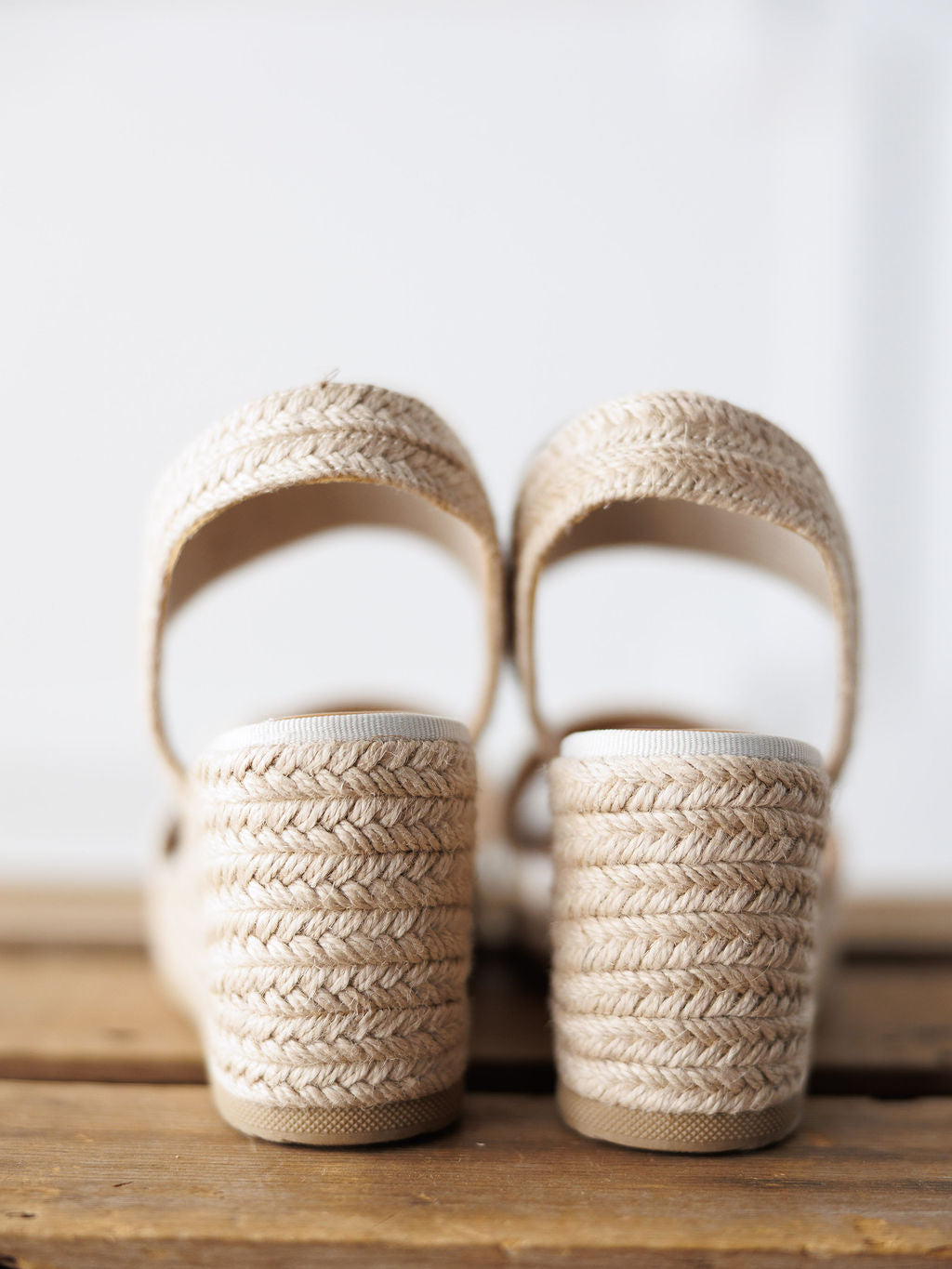 A close-up of The Abilene by Savannah Sevens western life{&}style—open toe beige woven wedge sandals with a gold snaffle bit and thick heels, displayed on wood with a white background.