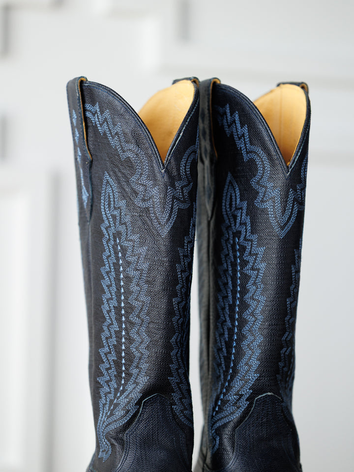 Close-up of The Pasadena boots by Savannah Sevens western life{&}style, featuring blue stitching and elegant midnight navy leather accents on the upper, set against a softly blurred background.