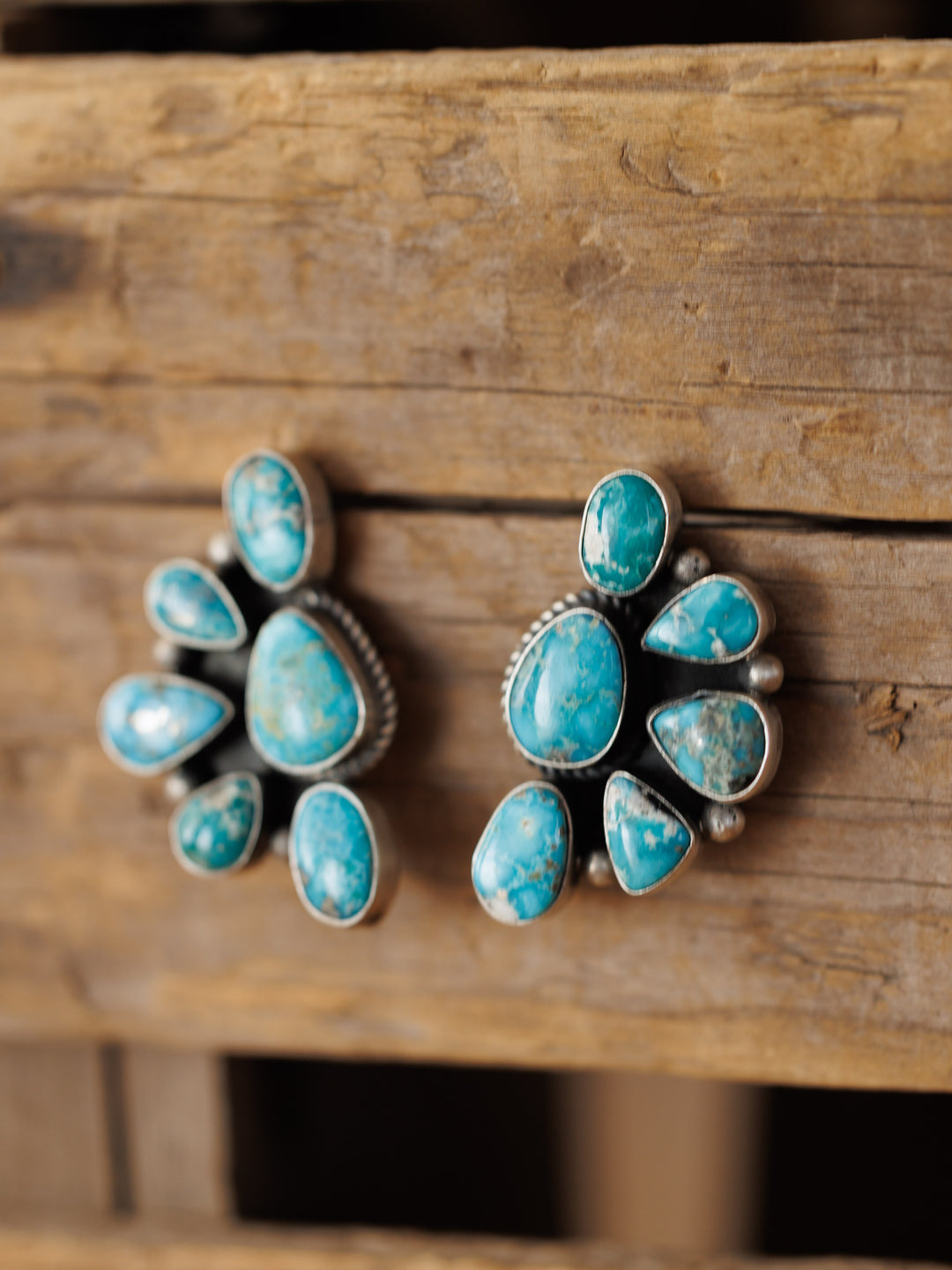 The Watseka Earrings by Savannah Sevens western life{&}style are Native American handcrafted turquoise clusters set in sterling silver, beautifully displayed on rustic wood.