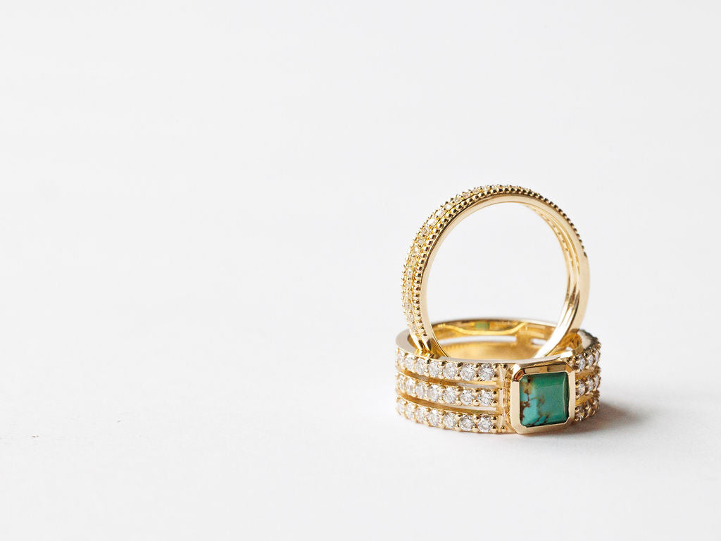 Three Savannah Sevens western life{&}style gold rings are stacked; two glitter with lab grown diamonds, while one Diamond Turquoise Ring features a striking square green gemstone. All are set against a plain white background.