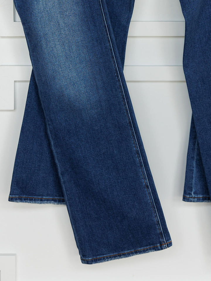 A close-up of The Bristol High Rise 90's Wide Leg Jean by Savannah Sevens western life{&}style in dark blue shows slight fading and visible hems, with the wide legs hanging against a white background.