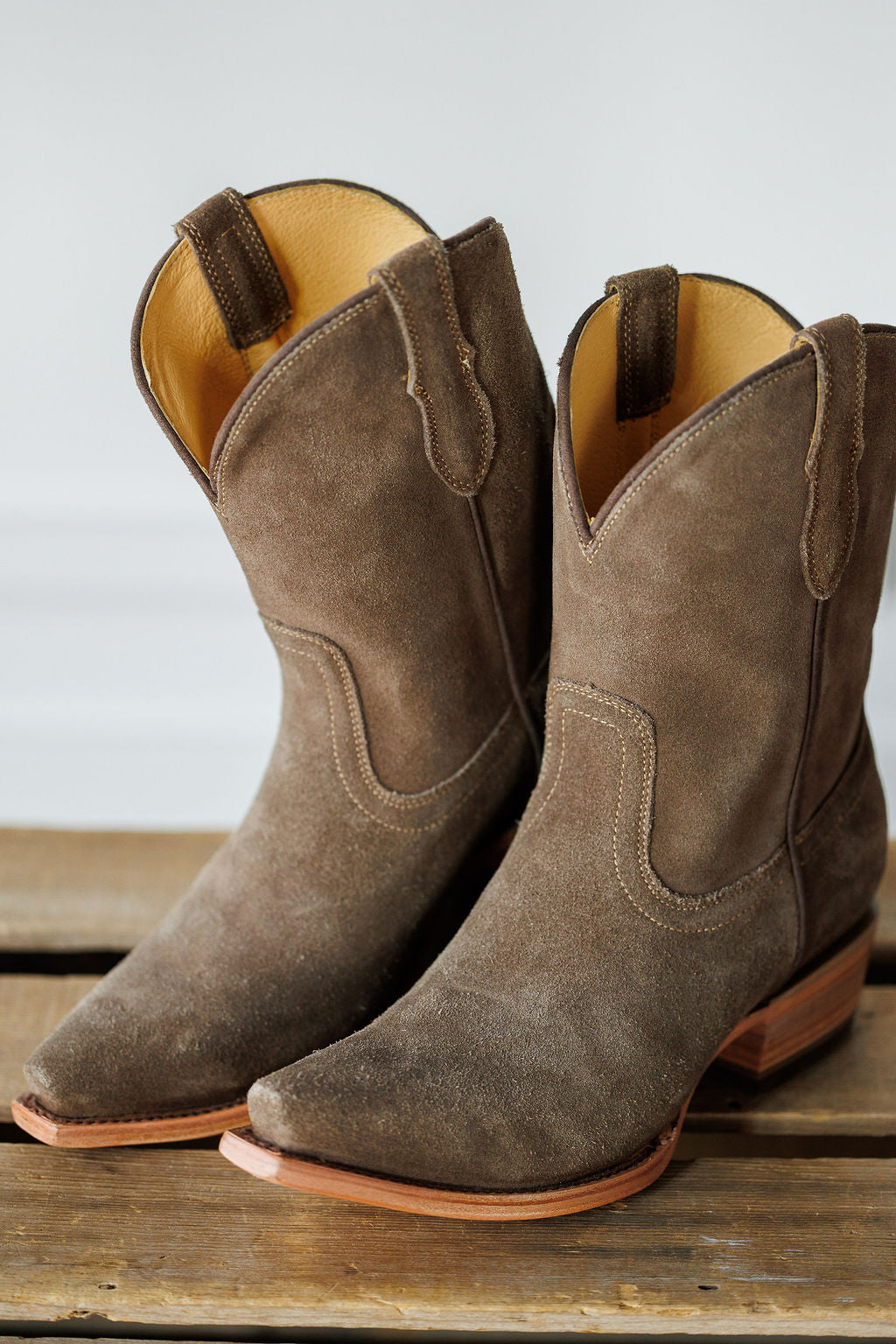 The Cordova by Savannah Sevens western life{&}style: brown rough out leather snip toe booties with wooden heels, shown side by side on a wooden surface. Boots by Blackstar. 