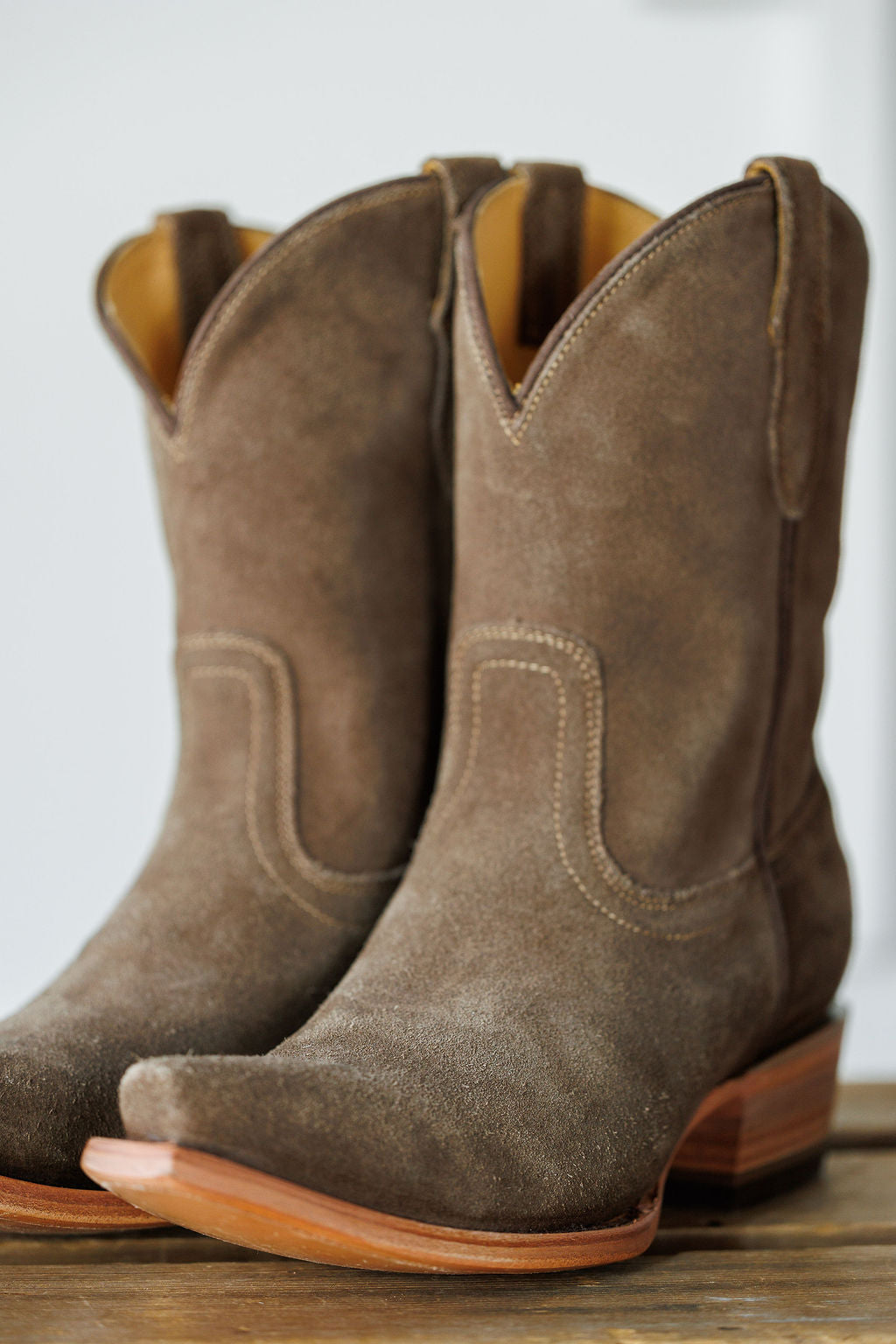 The Cordova by Savannah Sevens western life{&}style: brown rough out leather booties with snip toes, decorative stitching, and wooden heels, shown on a wooden surface. Made by Black Star. 