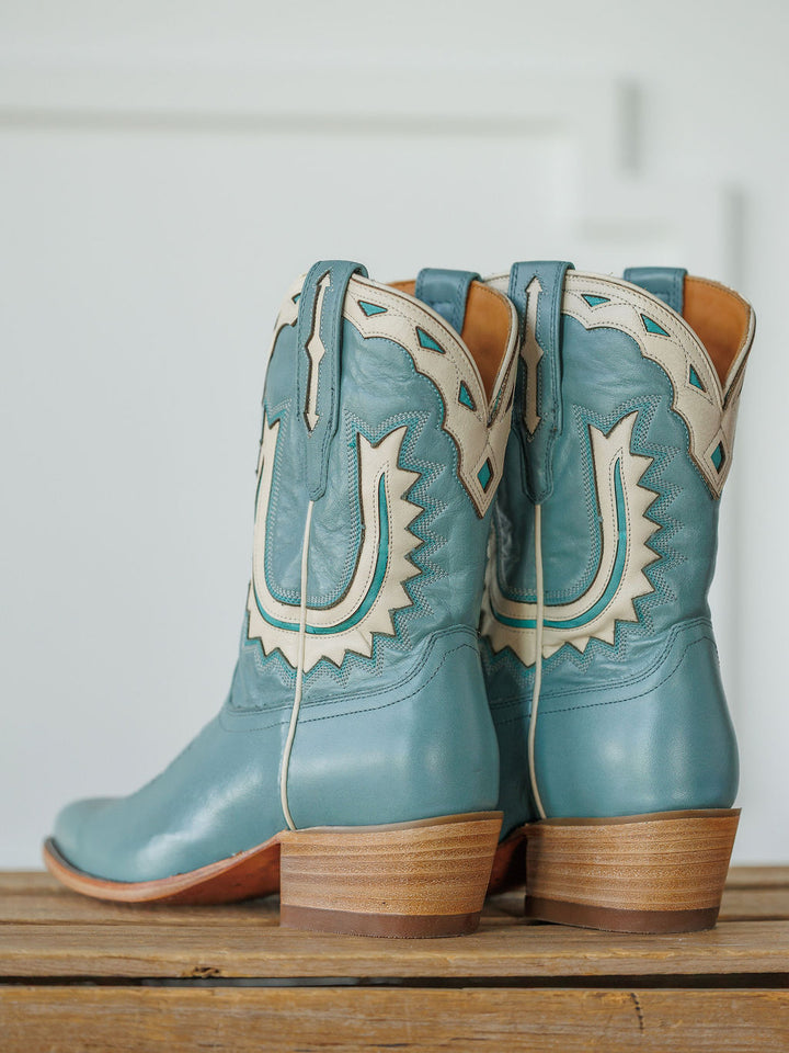The Jolene Boot {Seafoam} by Savannah Sevens western life{&}style: light blue cowhide leather boots with tan and white decorative stitching, shown on a wooden surface with a white background. Boots handmade by Tecovas.