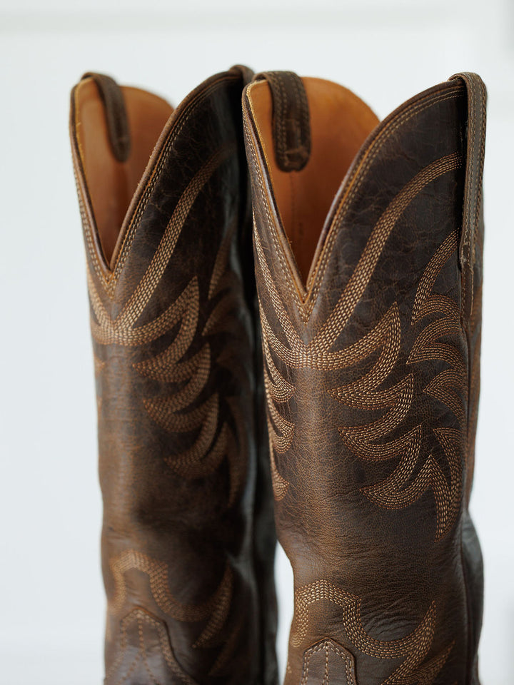 A close-up of The Annie Boot {Cafe} by Savannah Sevens western life{&}style shows two premium goat leather snip toe boots with intricate light stitching on the shafts and pull tabs at the top. Boots handmade by Tecovas.