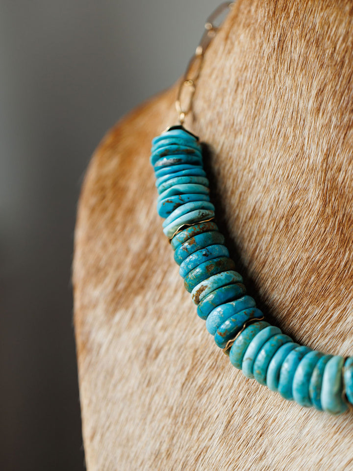Close-up of the Kingman Necklace by Savannah Sevens western life{&}style, featuring vibrant turquoise beads resting on soft, light brown cowhide.