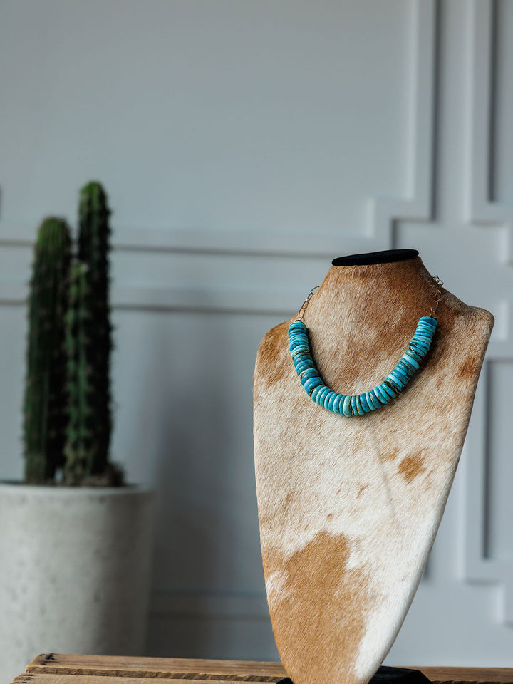 The Kingman Necklace by Savannah Sevens western life{&}style is shown on a tan and white cowhide bust, with a tall cactus in a white pot set against a white paneled wall in the background.