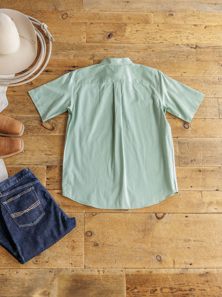 The Williamsburg men's shirt by Savannah Sevens western life&style is laid flat on a wooden floor, with jeans, brown boots, and a white cowboy hat arranged around it.