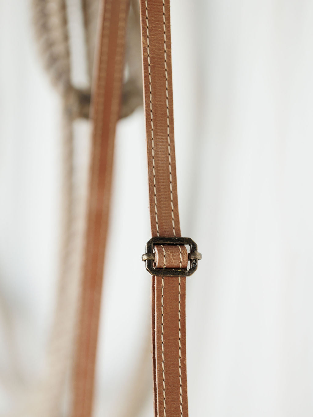 Close-up of The Lomita by Savannah Sevens western life{&}style—a brown leather strap with white stitching and a small metal buckle, perfect for accenting your favorite crossbody bag.