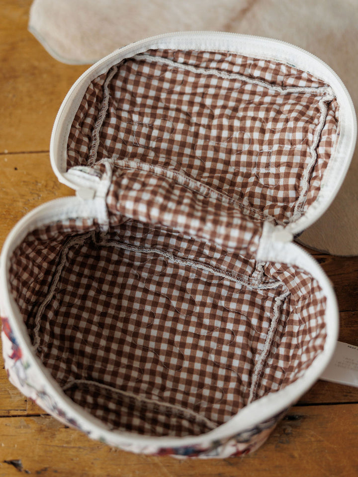 An open fabric pouch from the Cowgirl Gingham Collection by Savannah Sevens western life{&}style, featuring a brown and white vintage gingham lining, rounded shape, and visible edge stitching on a wooden surface.