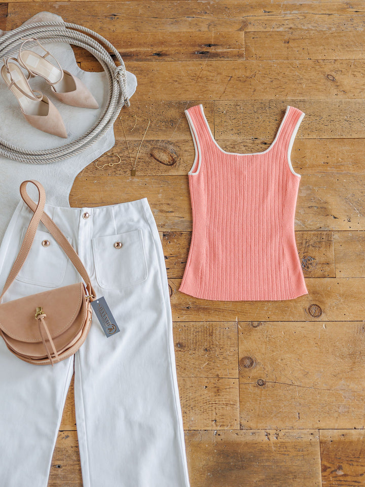 Flat lay featuring The Lasara tank top by Savannah Sevens western life{&}style, white high-waisted pants, a tan crossbody bag, beige pointed-toe flats, coiled rope, and a gold necklace on a wooden floor.