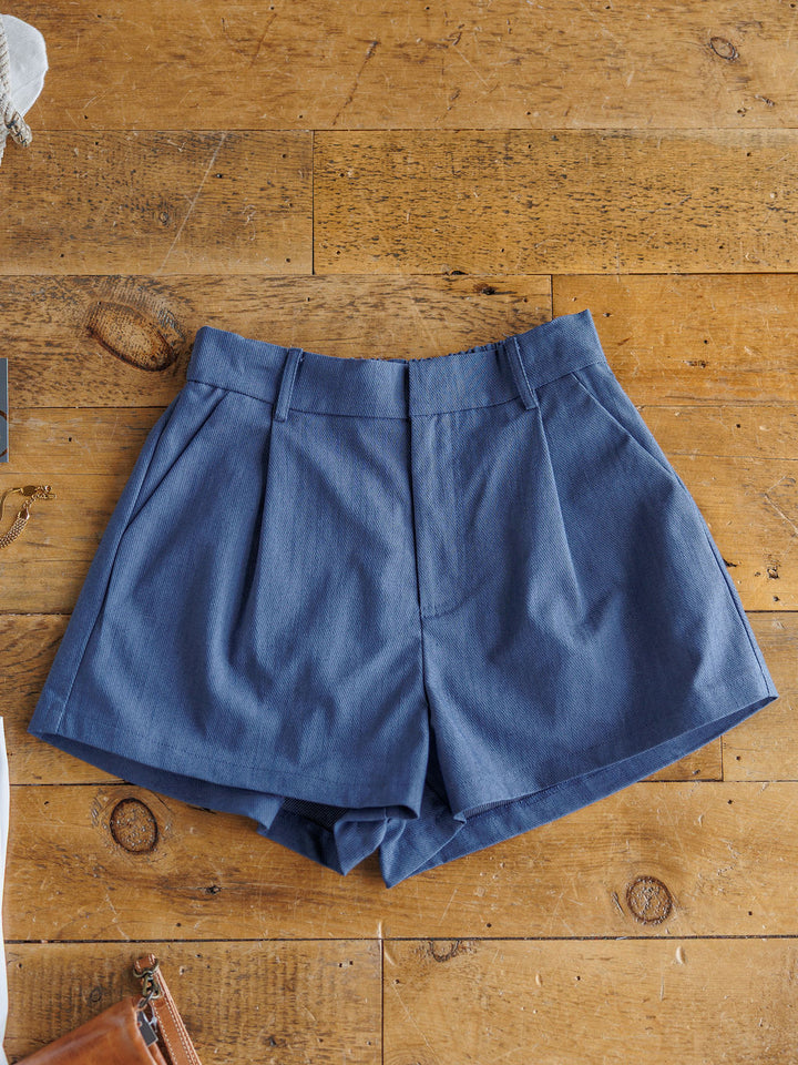 The Lenox high-waisted denim blue shorts by Savannah Sevens western life{&}style, made from a cotton blend with belt loops, are shown laid flat on a wooden surface.