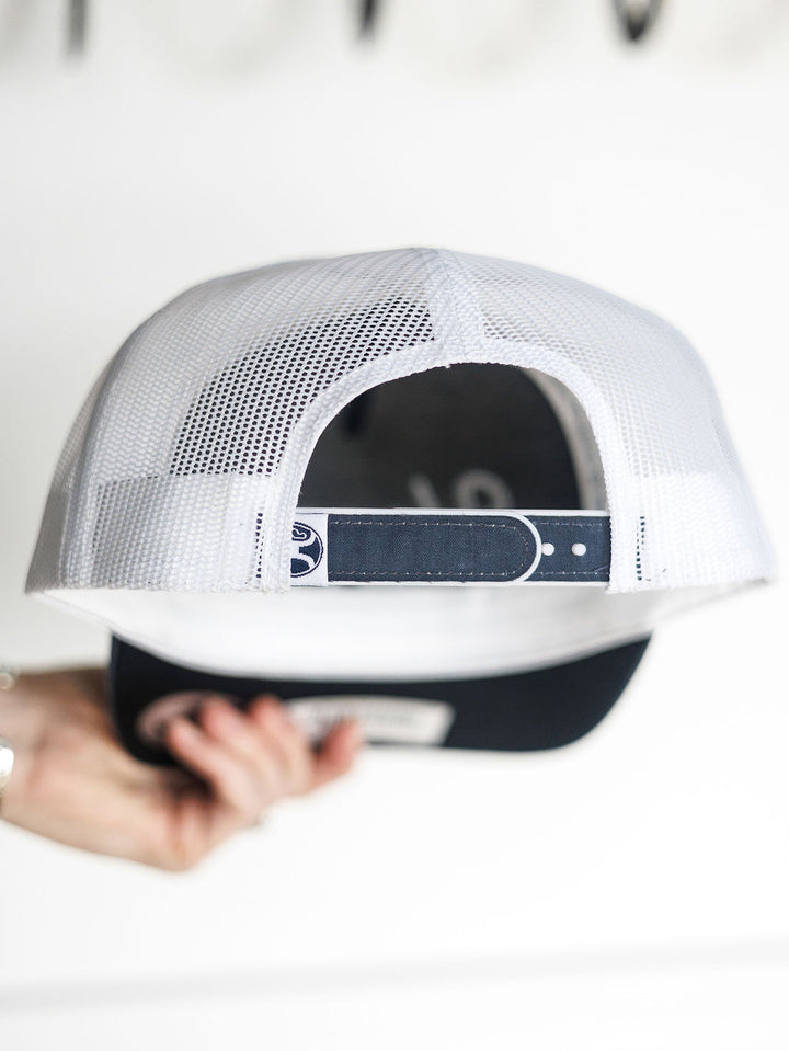 A hand holds the Hooey Colby Cap by Savannah Sevens western life{&}style, displaying its white mesh and adjustable snap back strap from the rear view.