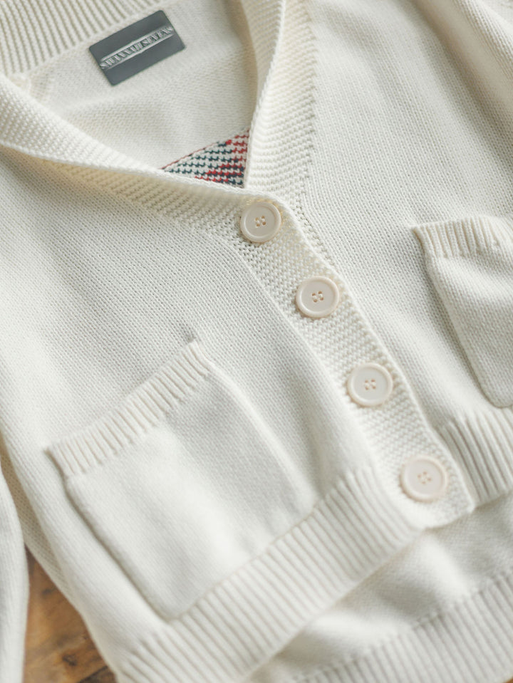 A close-up of The American Classic {Exclusive} cardigan by Savannah Sevens western life{&}style: cream-colored, 100% cotton, four beige buttons, two front pockets, textured collar, and a peek of colorful patterned fabric at the neckline.