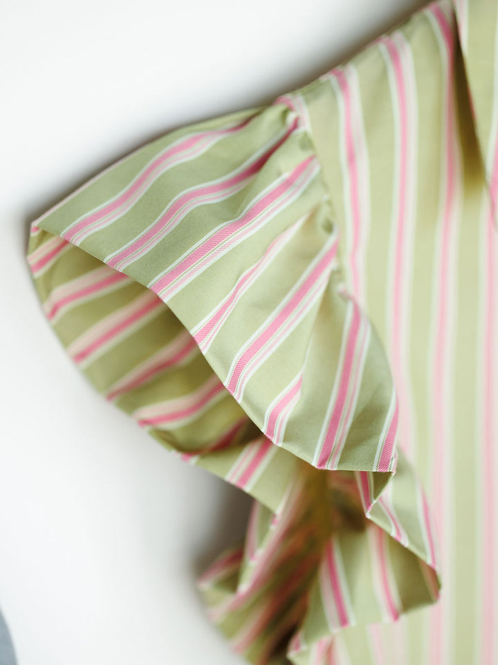 Close-up of the ruffled short sleeve on The Rayas sage pink blouse by Savannah Sevens western life{&}style, featuring white and pink vertical stripes. Soft fabric and flutter sleeve add a stylish, decorative touch.