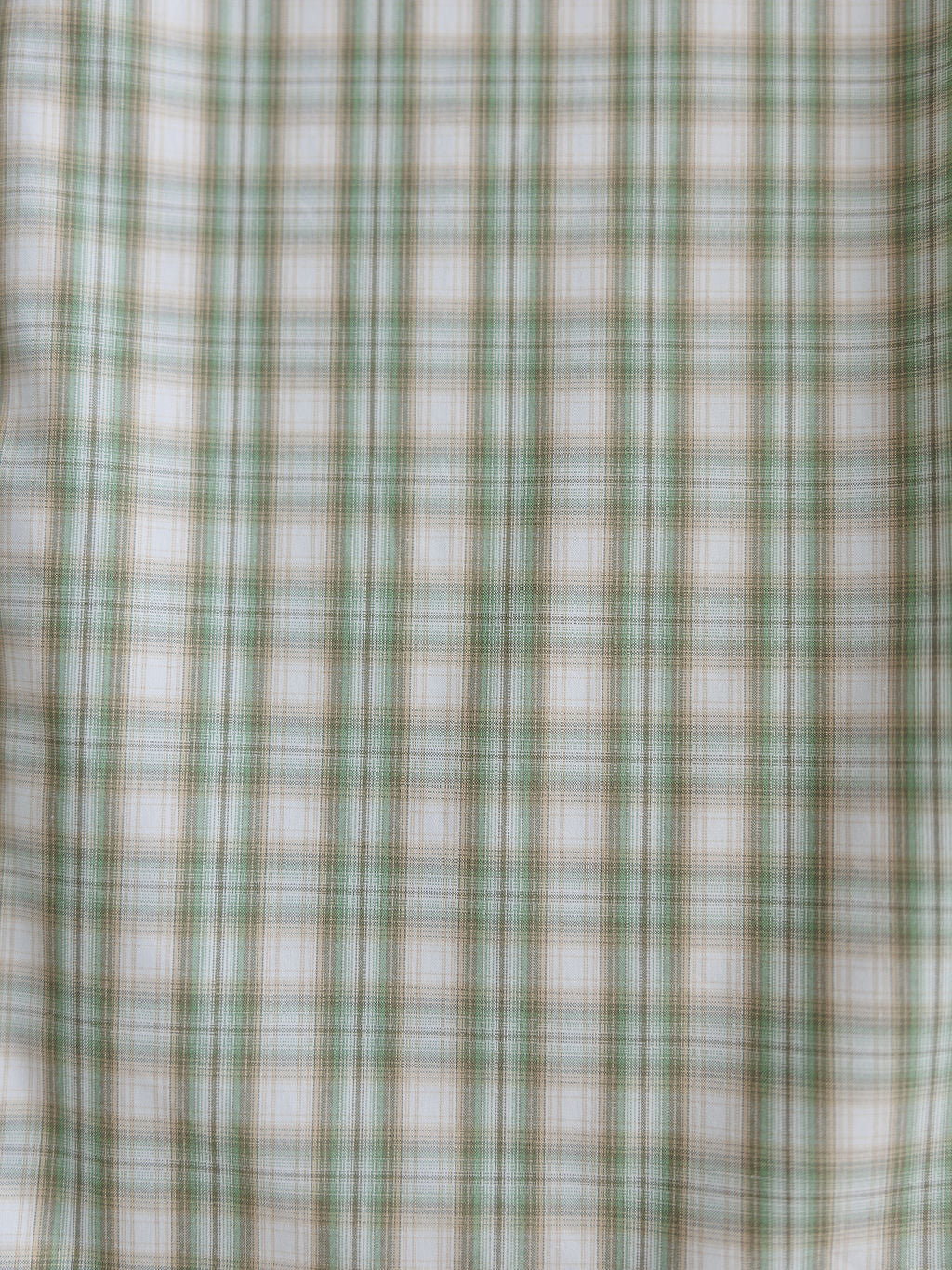 Close-up of The Eastwood men's shirt by Savannah Sevens western life{&}style, showing green and white plaid fabric with intersecting lines forming small squares. The material looks soft and slightly textured, ideal for a classic western style.
