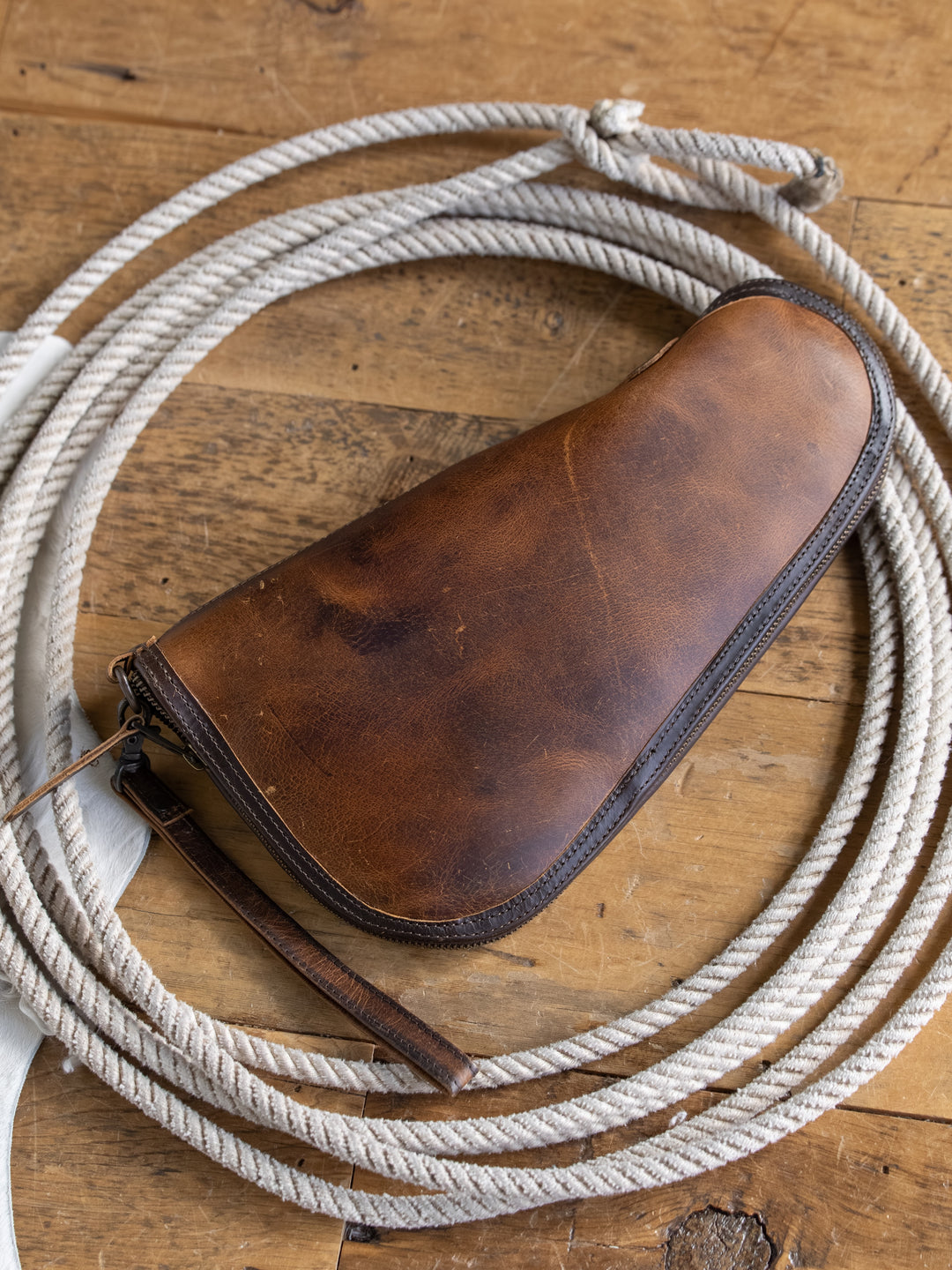 A Waynesboro Pistol Case by Savannah Sevens western life{&}style sits on a wooden surface, crafted from durable, stylish full grain brown leather.