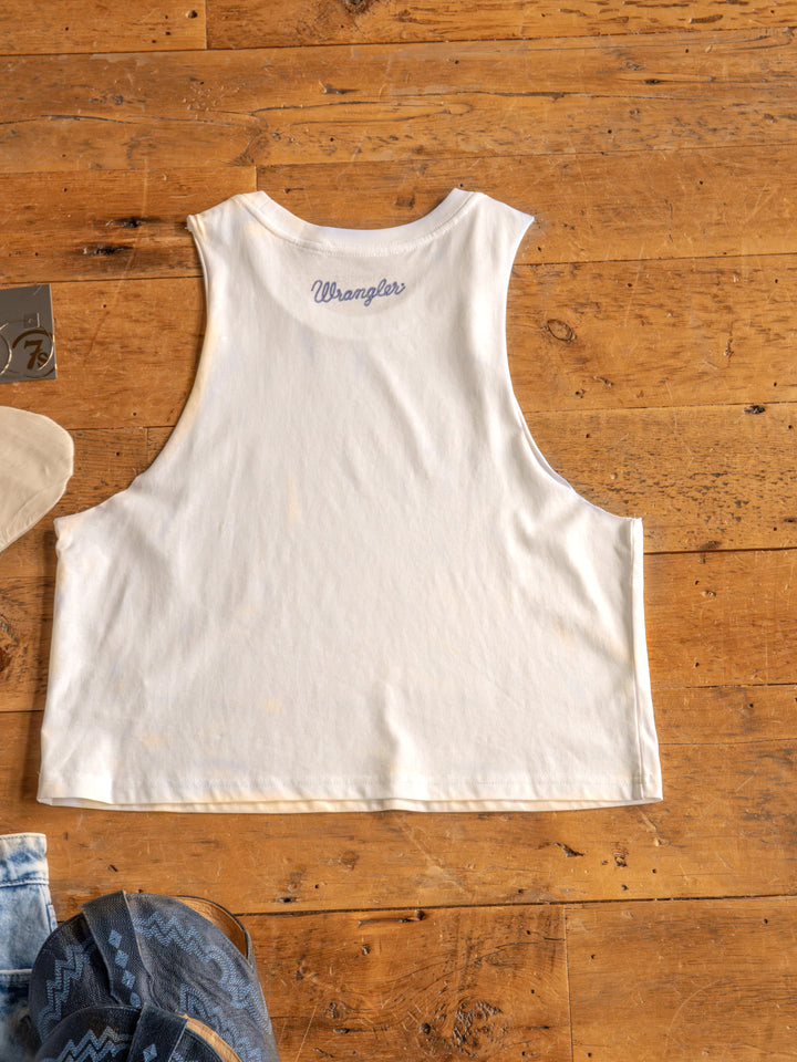The HBD America by Savannah Sevens western life{&}style is a sleeveless white muscle tank made from 100% cotton, laid flat on wood with denim and blue patterned fabric peeking out—perfect for celebrating Happy Birthday America.