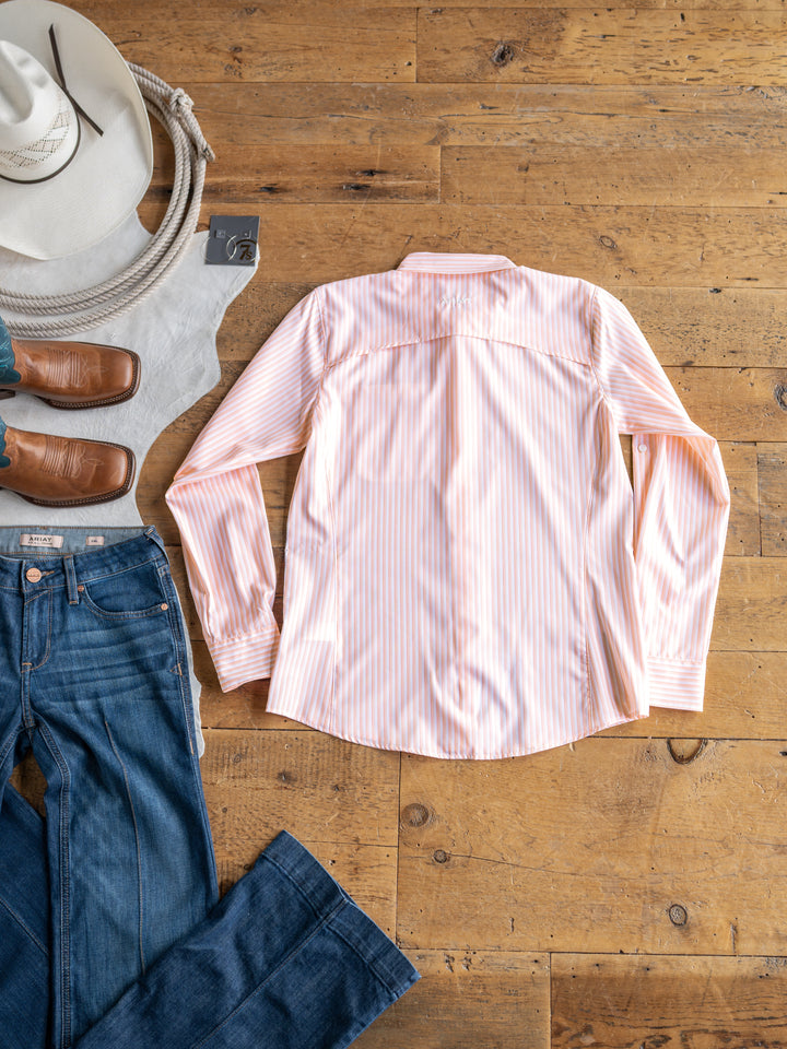 The Lovilia by Savannah Sevens western life{&}style, a pink and white striped long sleeve shirt, is laid flat with jeans, boots, a cowboy hat, and a rope. This moisture-wicking top delivers comfort and style for every adventure.