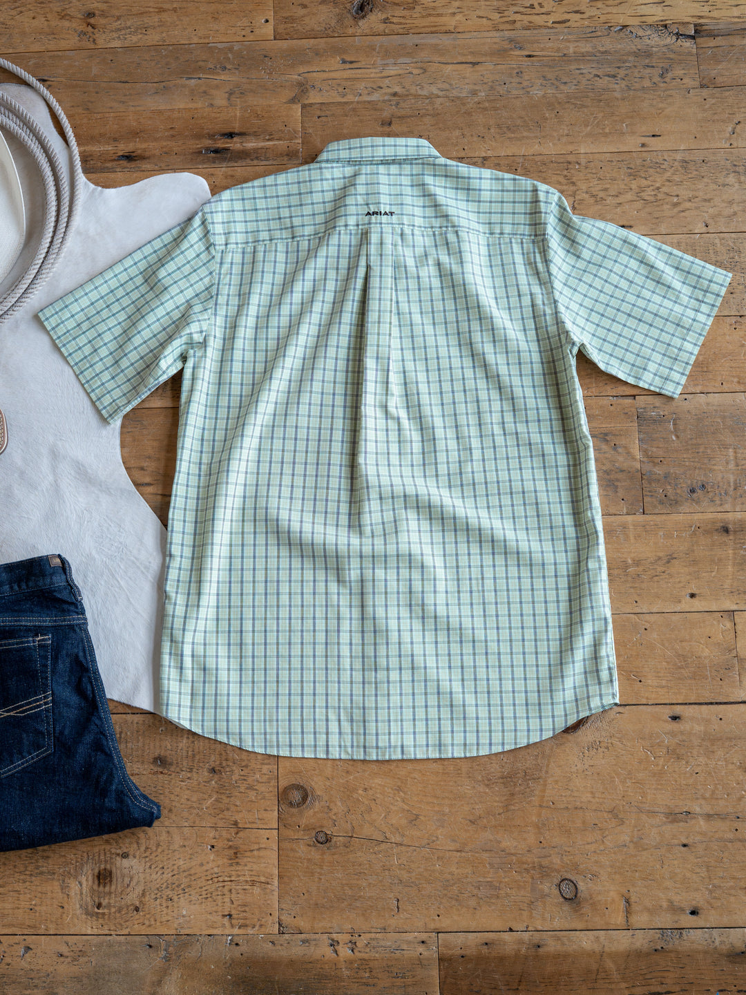 The Graham Men's by Savannah Sevens western life{&}style: light green plaid short sleeve button-up with a blue checkered pattern, shown with jeans and a white rug. Wrinkle-free fabric keeps it looking crisp all day.