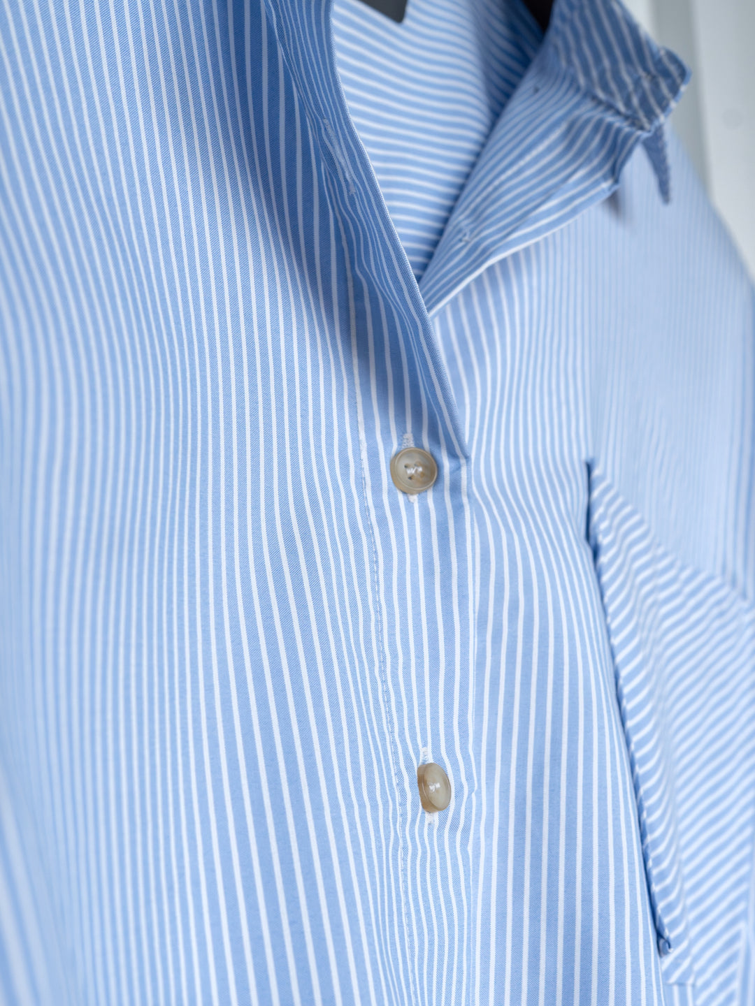 A close-up of The Driscoll by Savannah Sevens western life{&}style, featuring an ice blue and white pinstripe button-up top with two beige buttons and a partial chest pocket.