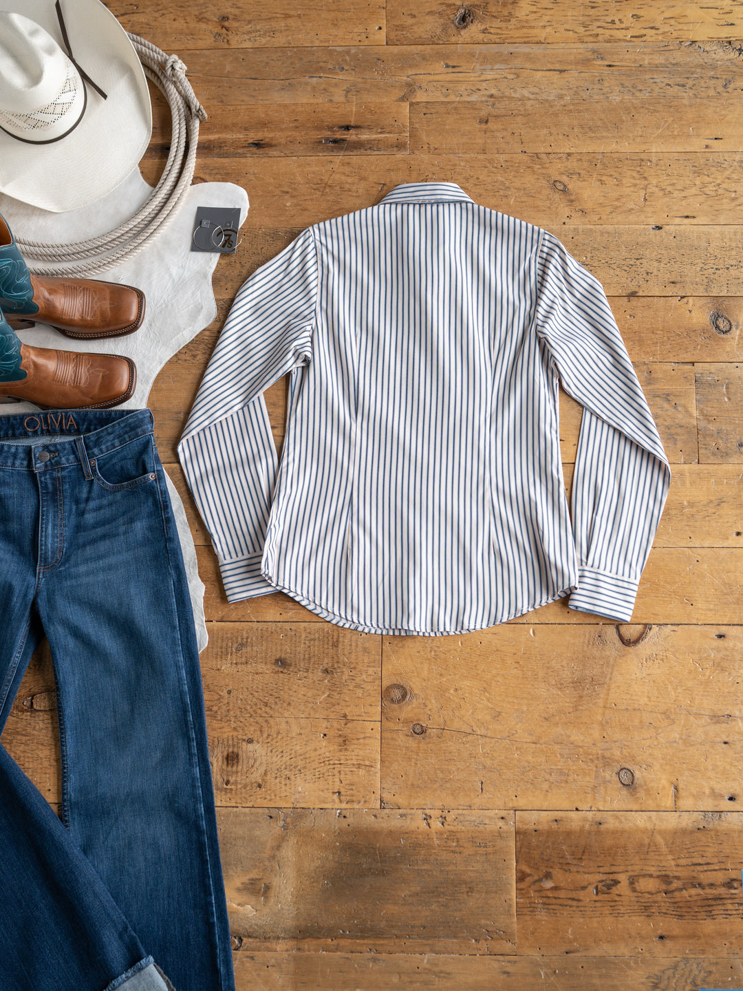 The Durant {S-XXL} tencel top from Savannah Sevens western life{&}style is styled flat with blue jeans, brown leather boots, a white cowboy hat, and a white sweater on a wooden floor.