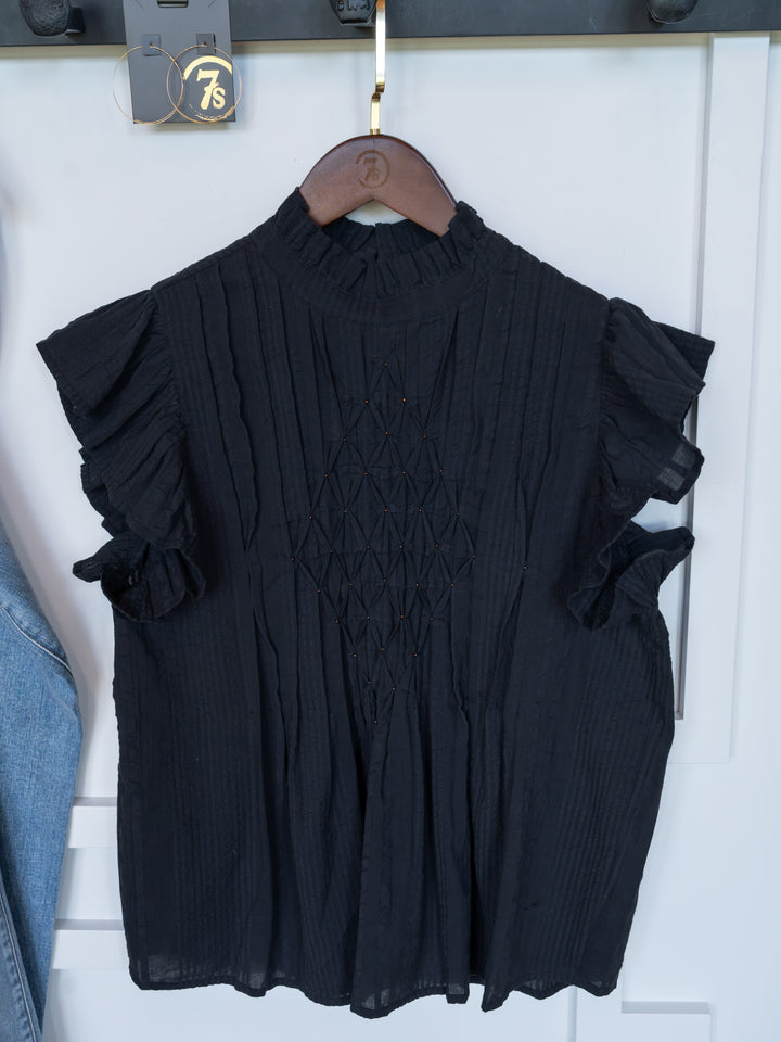 The Winnett by Savannah Sevens western life{&}style is a midnight navy short sleeve top with ruffled sleeves, a high neck, and a diamond-textured front, shown on a wooden hanger against a white background.