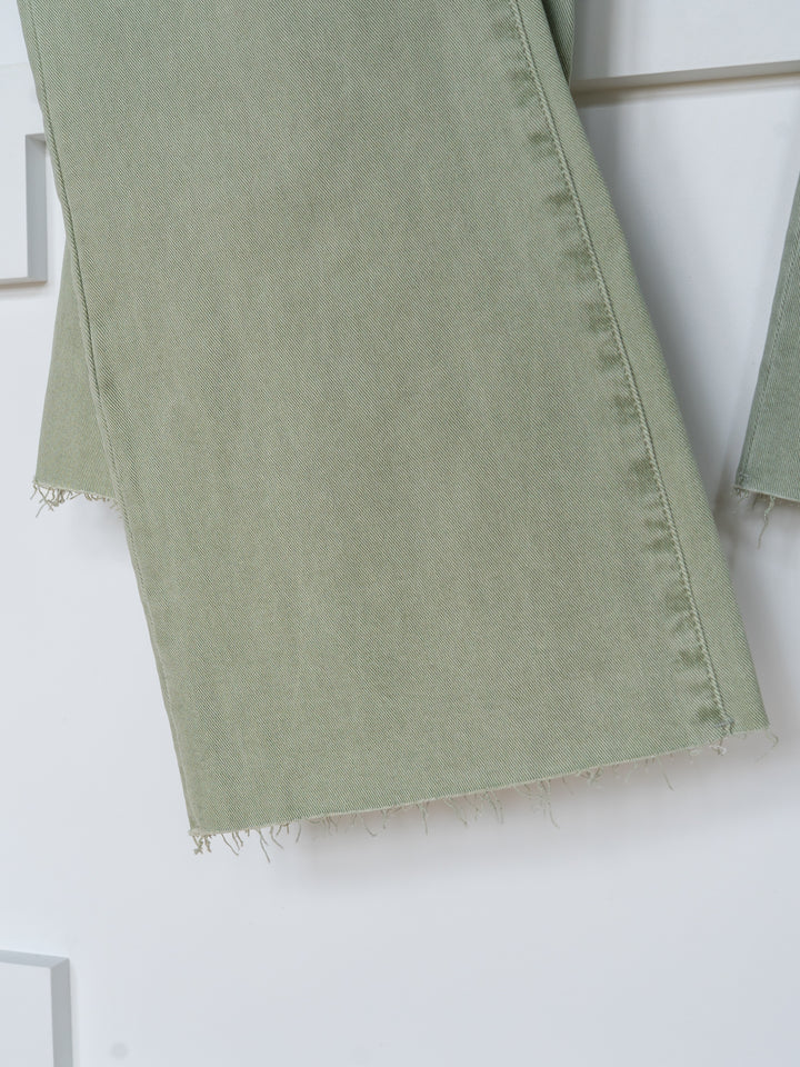 Close-up of The Lindy High Rise Wide Leg Jean by Savannah Sevens western life{&}style, featuring sage denim pant legs with a raw cut hem, hanging against a white background.