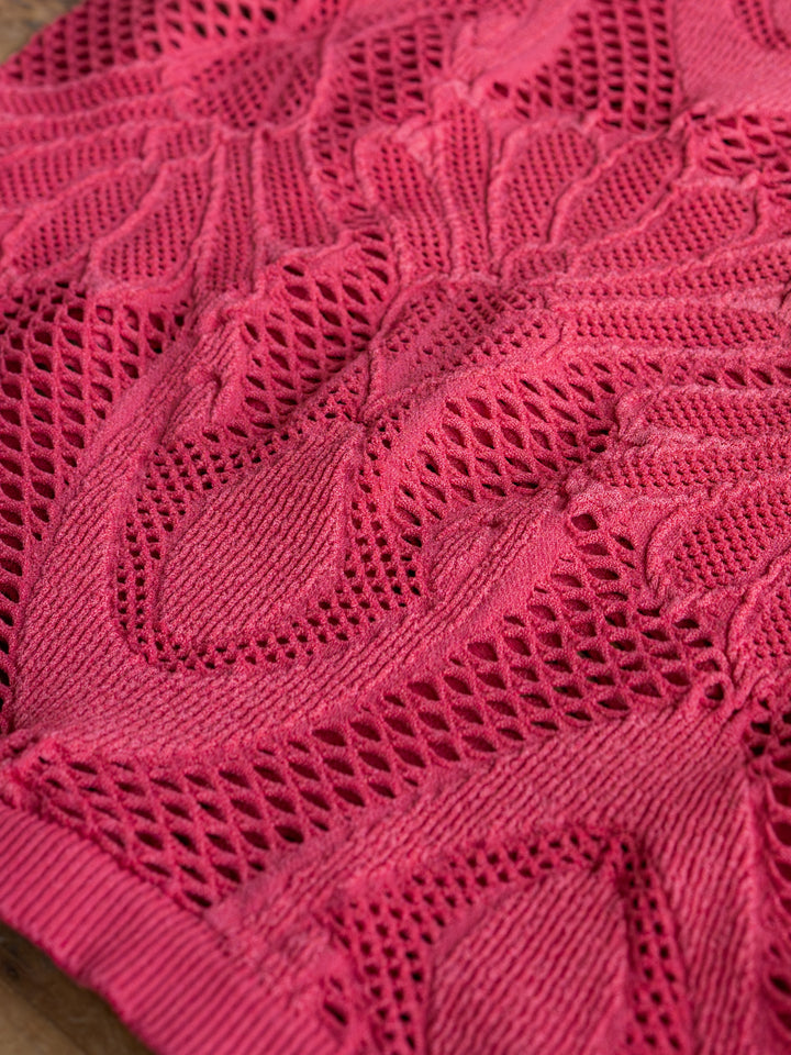 Close-up of The Lexa crochet top by Savannah Sevens western life{&}style in raspberry red, showcasing intricate patterns and mesh-like openwork with soft textured material and detailed woven elements.