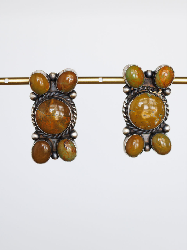 The Yuma Earrings by Savannah Sevens western life{&}style are vintage handcrafted sterling silver pieces, each with a large round orange-brown center stone and four smaller oval orange and green stones, shown on a plain white background.