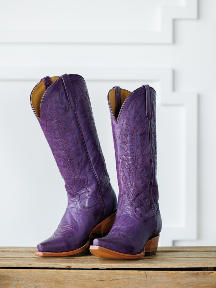 The Maricopa by Savannah Sevens western life{&}style: tall plum leather snip toe western boots with decorative stitching, shown side by side on a wooden surface against a white geometric-patterned background. Made by Black Star. 