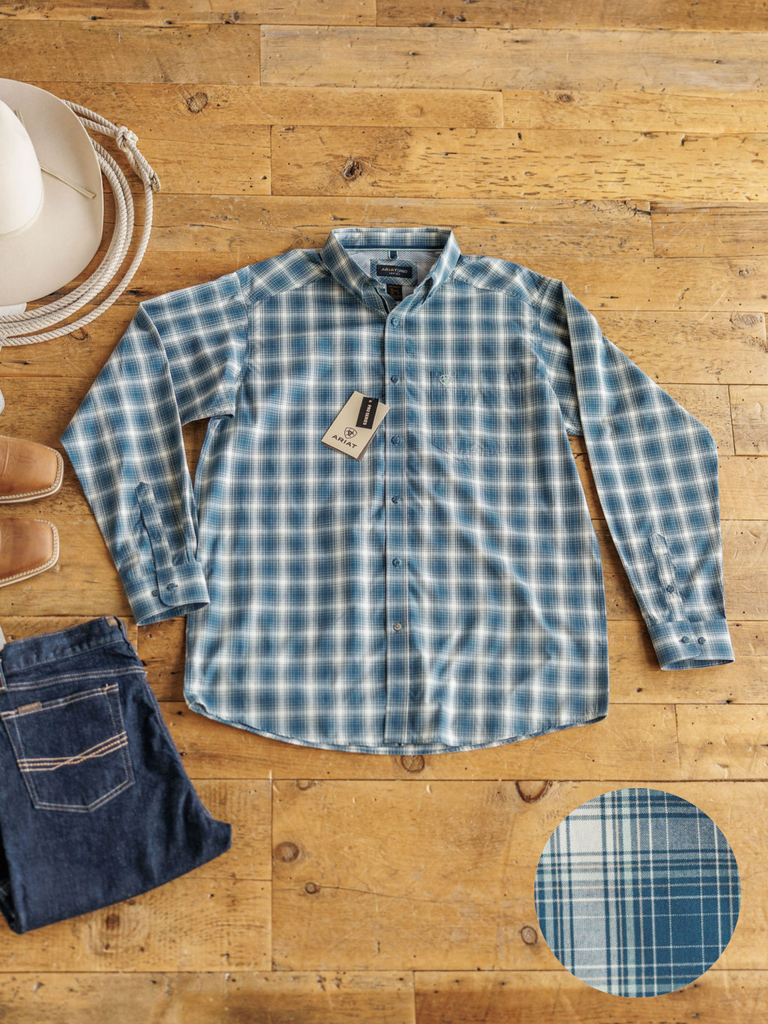 The Davis men’s shirt by Savannah Sevens western life{&}style is a blue and white plaid, long-sleeve top shown flat with a white hat, coiled rope, brown shoes, and jeans. It offers sun protection; close-up reveals its detailed fabric pattern.