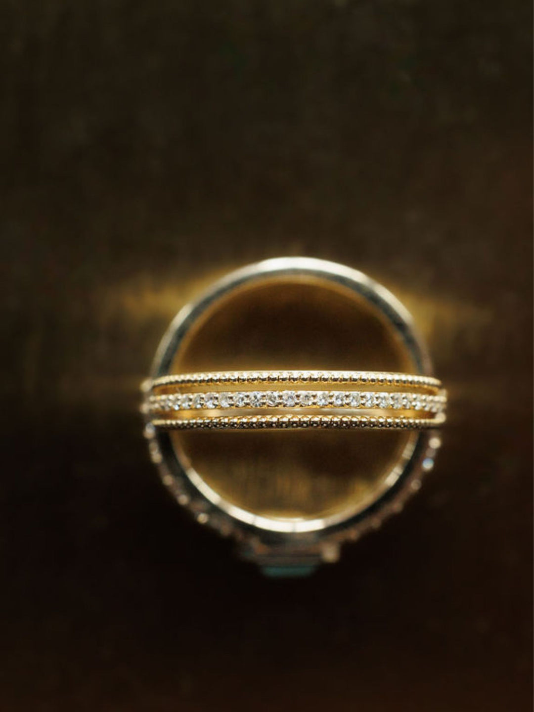 A close-up of two Savannah Sevens western life{&}style Diamond Milgrain Rings in 14K gold, stacked together. One ring features a row of small diamonds and delicate milgrain details, set against a dark, blurred background. Collaboration the Devereaux Gold.
