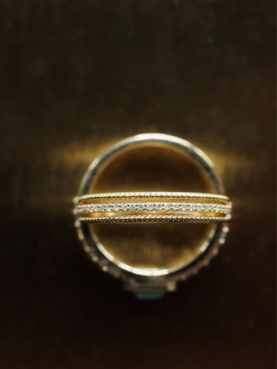 A close-up of two Savannah Sevens western life{&}style Diamond Milgrain Rings in 14K gold, stacked together. One ring features a row of small diamonds and delicate milgrain details, set against a dark, blurred background. Collaboration the Devereaux Gold.