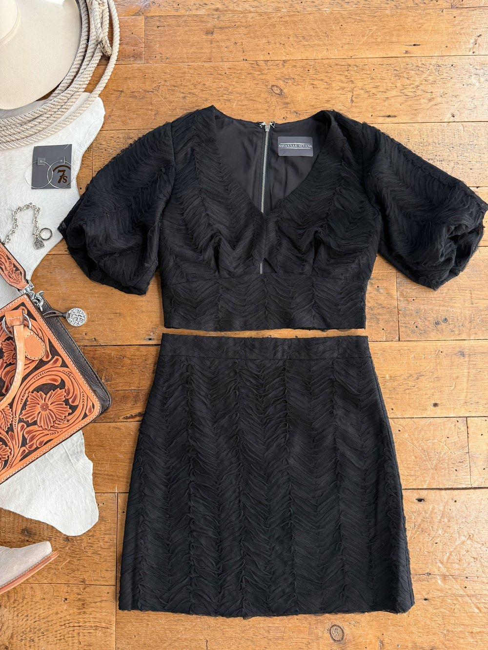 Black dress on a wooden surface with accessories around