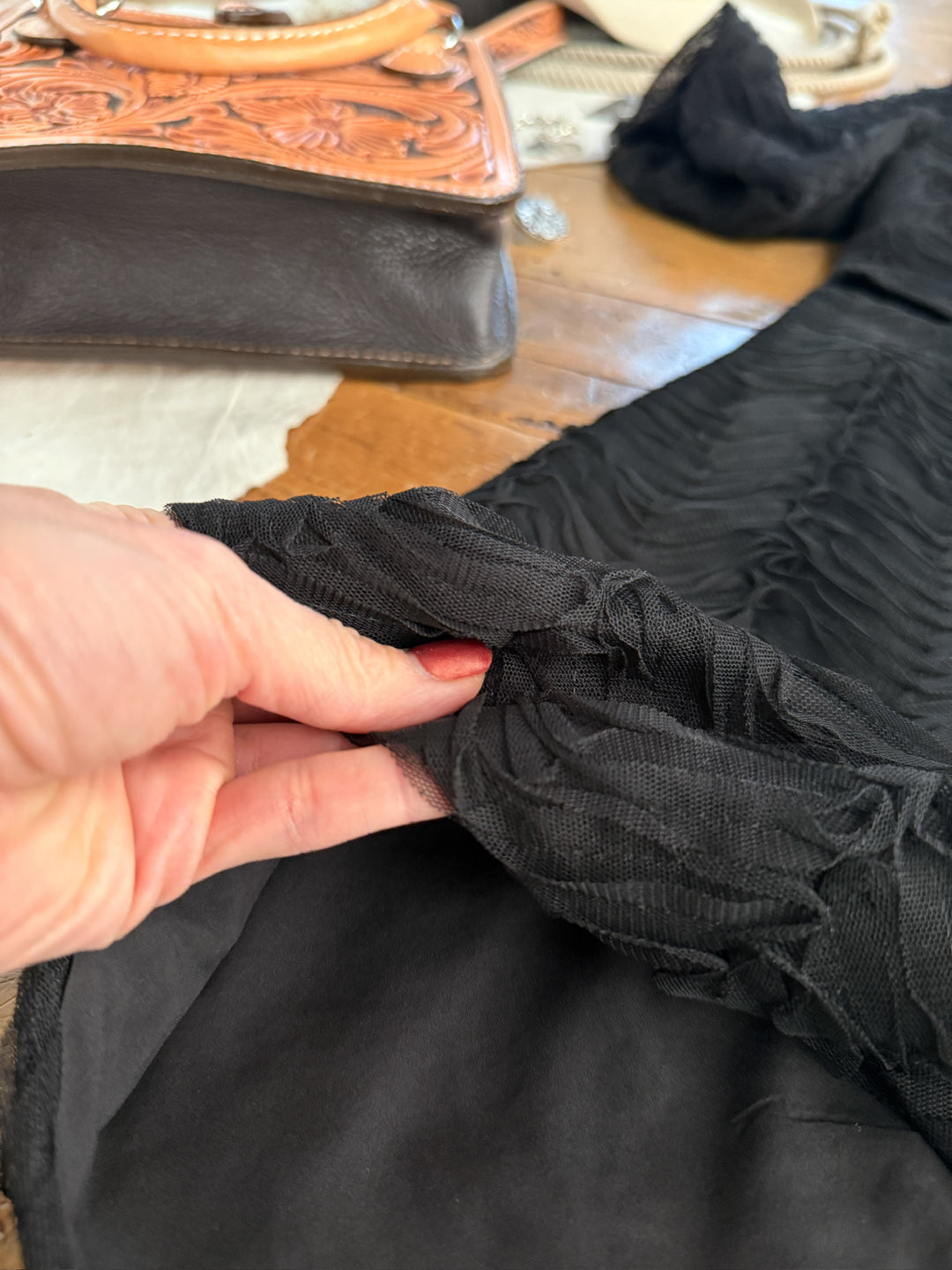 Close-up of a hand holding black fabric with a wooden surface in the background